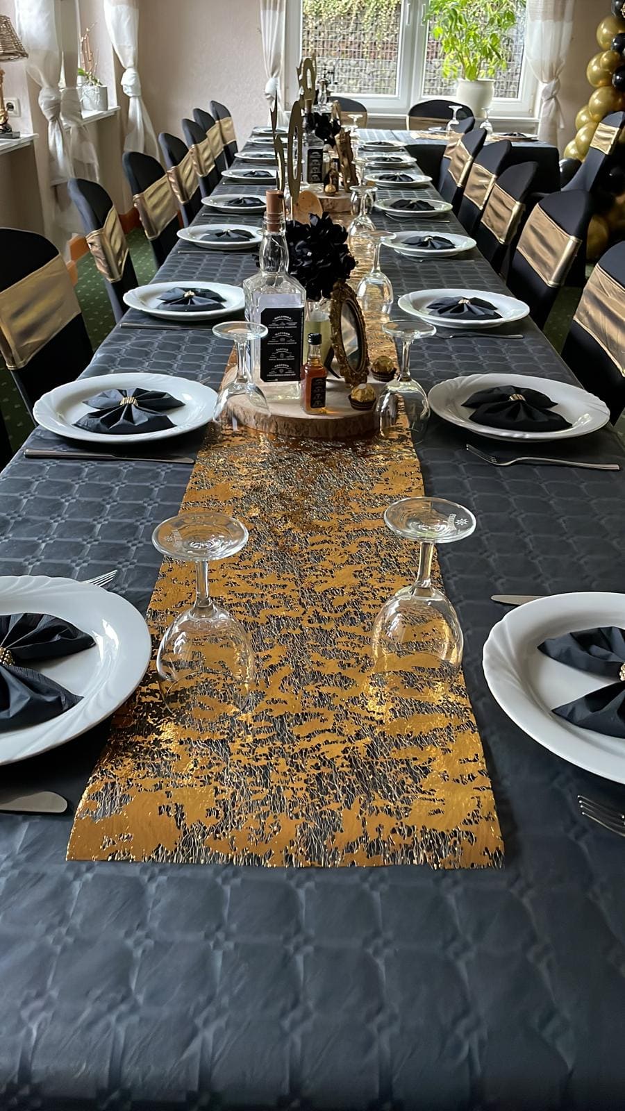 Eingedeckte Festtafel im Landhaus Schend mit goldenem Tischläufer, schwarzen Servietten und Sektgläsern
